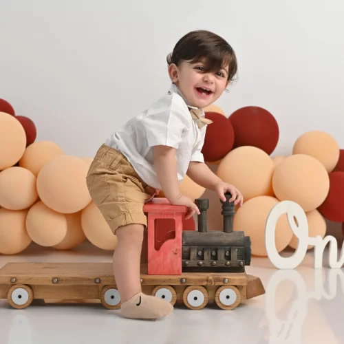 عکاسی تولد یک سالگی نوزاد پسر با عروسک قطار و بادکنک های رنگی در استودیو عکاسی گلسا