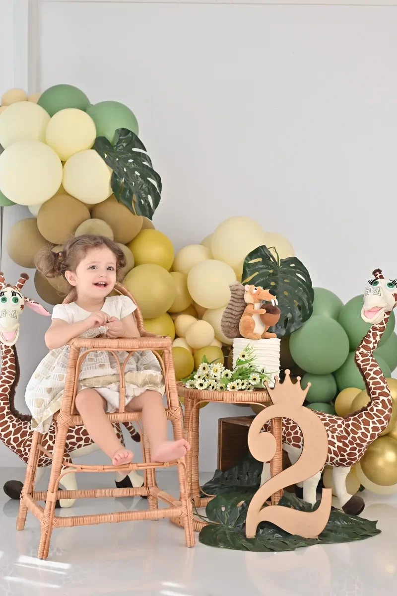 عکاسی تولد دو سالگی در استودیو گلسا با دکور عدد 2 و بادکنک رنگی و عروسک زرافه و سنجاب و صندلی چوبی